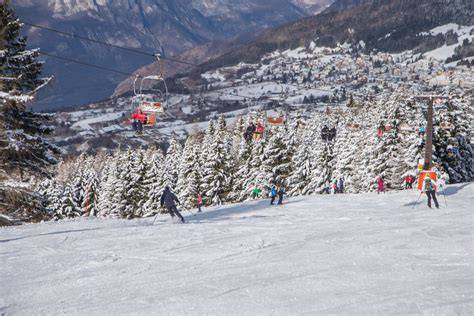 Vista panoramica delle piste da sci su Alpe Cimbra con sciatori che scendono.