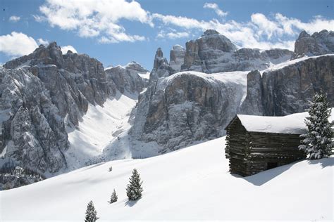 Panoramica delle vette innevate delle Dolomiti, con sciatori che scendono su un pendio aperto.