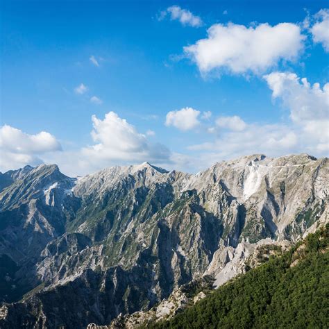 Panorama delle Alpi Apuane con cime innevate, in lontananza si intravede il mare.