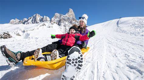 Famiglia che si diverte a sciare e fare slittino a Dobbiaco