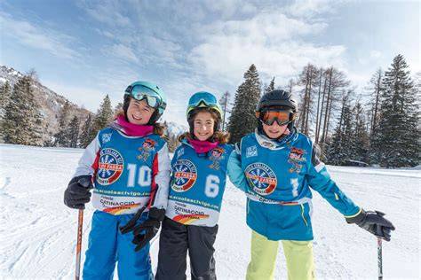 Famiglia sorridente che si prepara a sciare davanti a un hotel di montagna