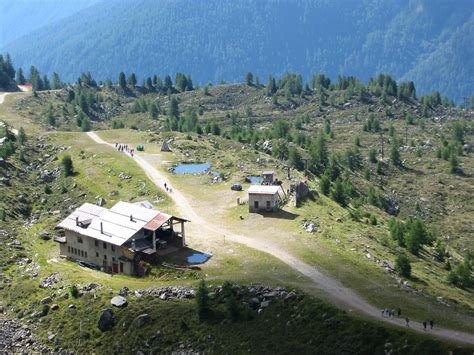 Vista panoramica dalle montagne circostanti il Rifugio Doss dei Cembri, con cime innevate e valli verdi