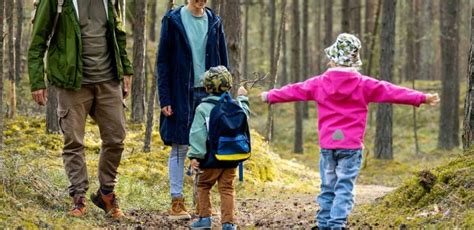 famiglia che passeggia su un sentiero nel bosco con le montagne sullo sfondo