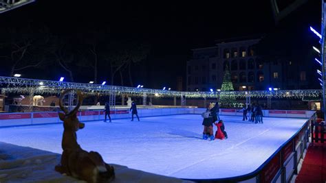 Pista di pattinaggio su ghiaccio natalizia in una piazza cittadina con alberi decorati