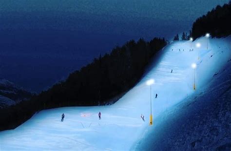 Vista panoramica della pista da sci Colverde illuminata di notte con le montagne innevate sullo sfondo