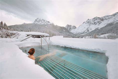 persona che si rilassa in una piscina termale all'aperto con vista sulle montagne innevate