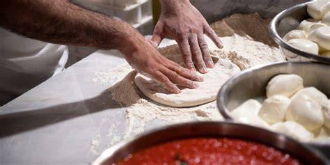 foto di un pizzaiolo che stende l'impasto della pizza con cura