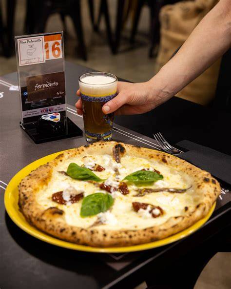 selezione di bottiglie di birra artigianale accanto a una pizza appena sfornata
