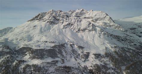 Vista panoramica mozzafiato delle cime innevate del Monte Corvo con un ampio pendio sciabile.