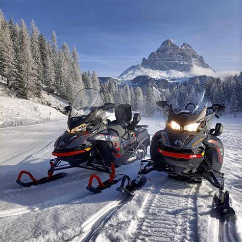 motoslitta che trasporta persone sulla strada innevata verso le Tre Cime di Lavaredo