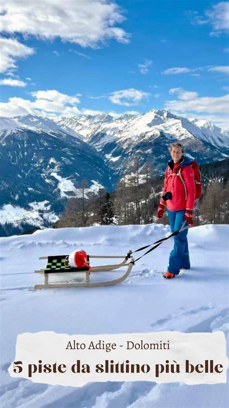 slittino che scende lungo una strada innevata con le montagne sullo sfondo