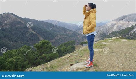 Giovane donna guarda il paesaggio nuvoloso dalla cima di una montagna all'alba, montagne della costa occidentale del Pacifico, British Columbia.