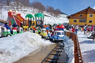 Bambini che giocano sulla neve con una mascotte (Yepi) e slittini