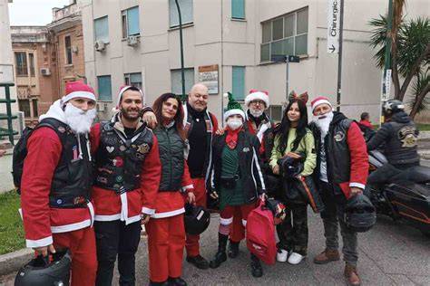 Gruppo di motociclisti vestiti da Babbo Natale mentre consegnano regali ai bambini in ospedale