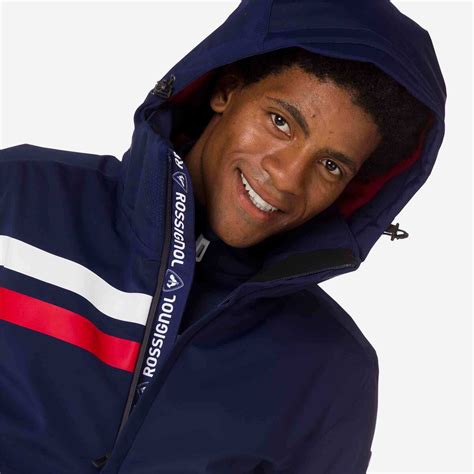 Un ragazzo sorridente con indosso una giacca da sci Rossignol azzurra, pronto per sciare.