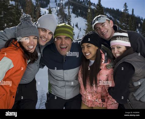 Un gruppo di persone sorridenti che indossa ciaspole e cammina su un sentiero innevato in montagna.