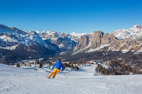 Sciatori su una pista ben battuta nelle Dolomiti con cime innevate sullo sfondo
