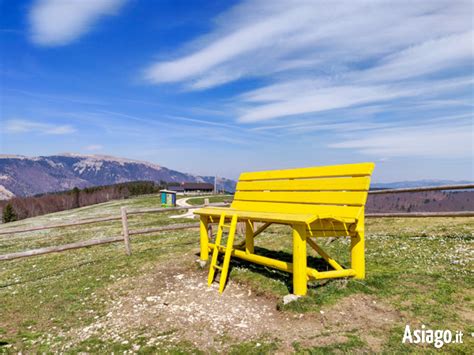 La panchina gigante gialla di Asiago con un vasto panorama sullo sfondo
