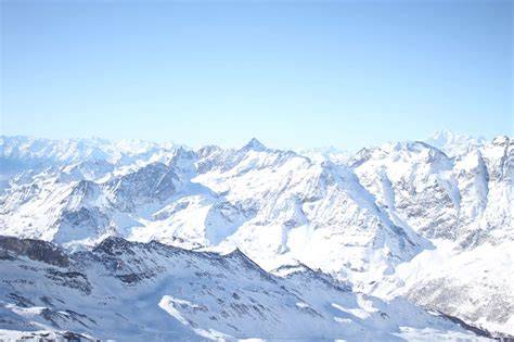 Panoramica delle montagne innevate della Valle d'Aosta, con una persona che fa snowboard in lontananza