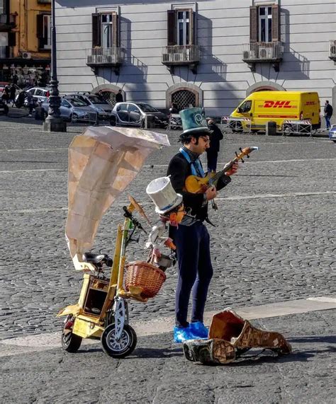 Foto di un artista di strada vestito da Sciò Sciò che interagisce con turisti in una via di Napoli.