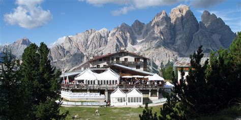 Vista panoramica del Rifugio Faloria con la terrazza e le montagne circostanti.