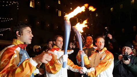 Una foto della staffetta della torcia olimpica che attraversa una città italiana durante il percorso verso Torino 2006.