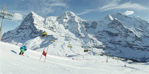 Panorama alpino con la pista Lauberhorn in primo piano e le cime dell'Eiger, Mönch e Jungfrau sullo sfondo.