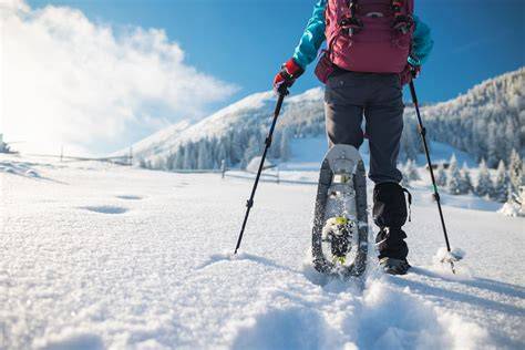Ragazza sorridente che indossa guanti Ziener colorati, in piedi sulla neve con uno sfondo di montagne.